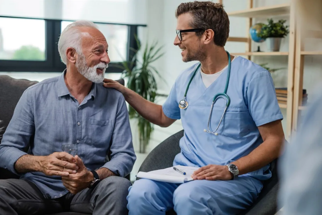 Man meeting with his GP both smiling and talking