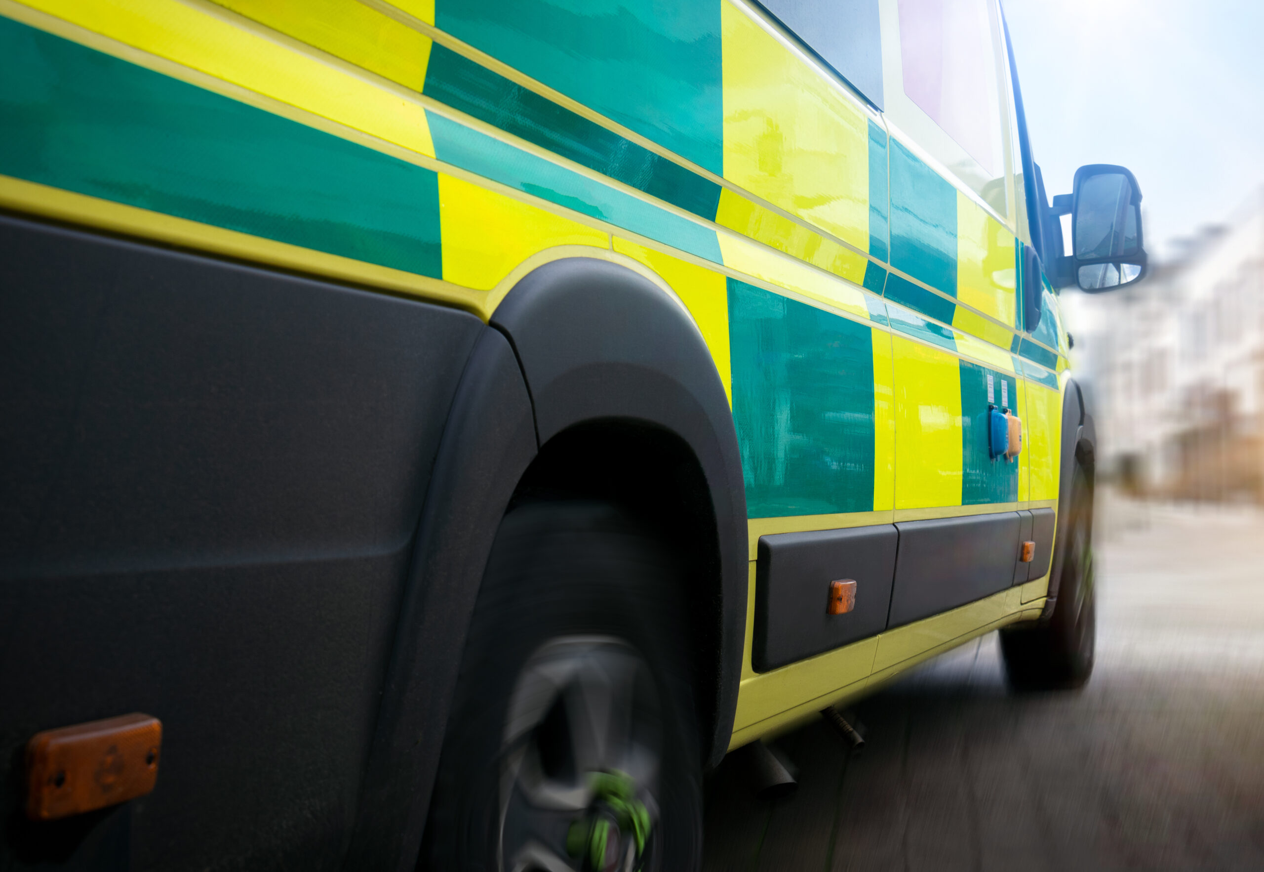 Close up of the side of an ambulance driving down a road