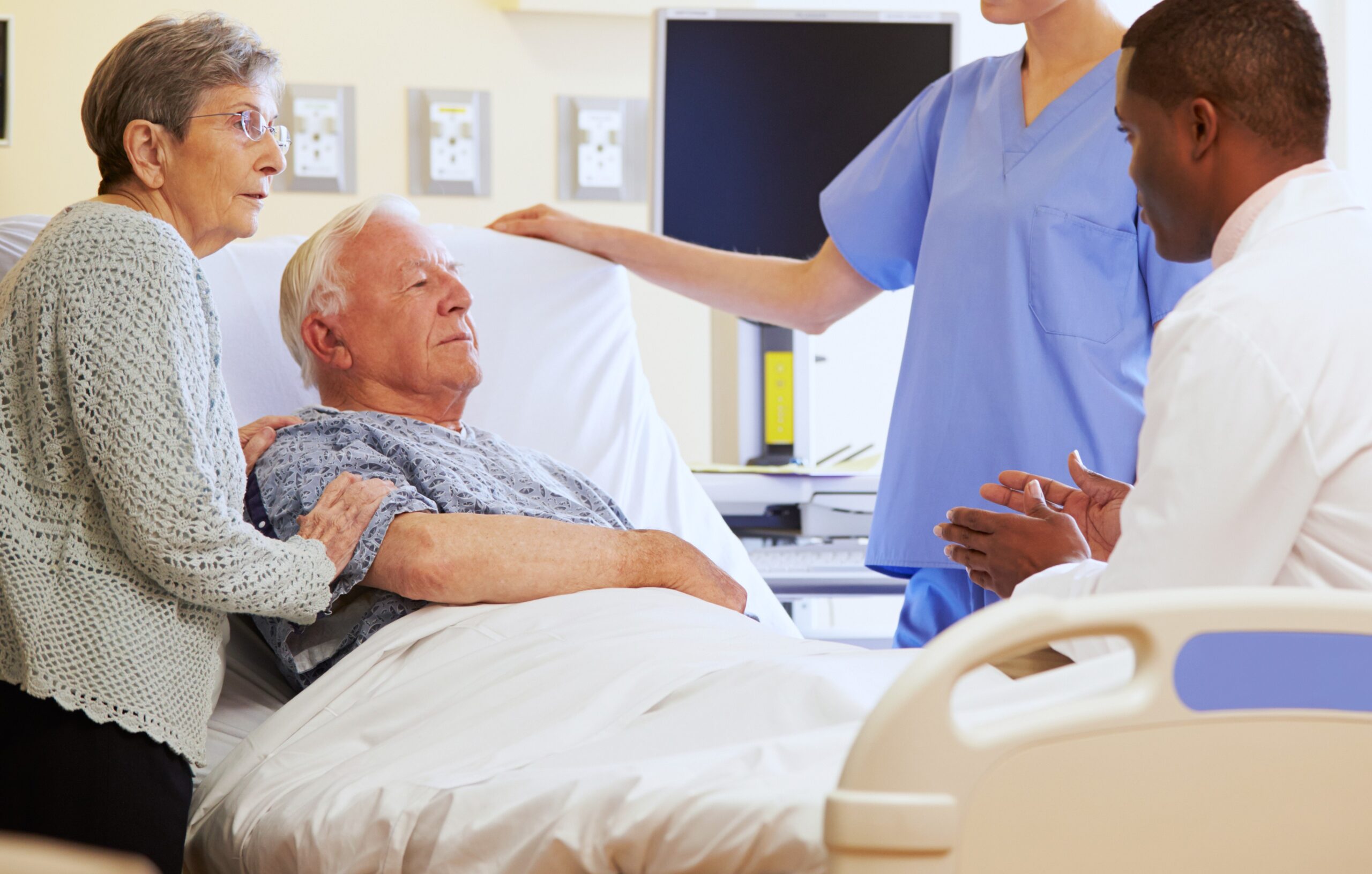 hospital bed discussion between healthcare staff and patient with family