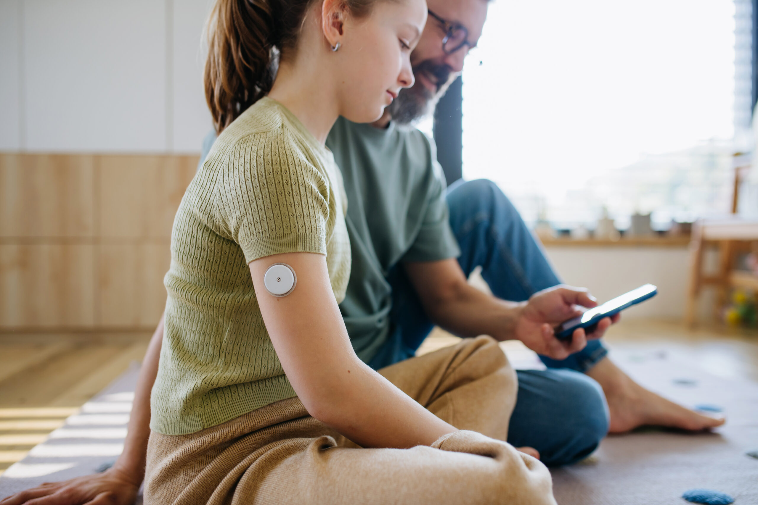 Diabetic girl with a CGM sensor on her arm.