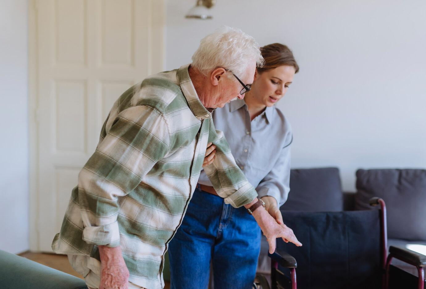 Carer holding hand and helping man at home