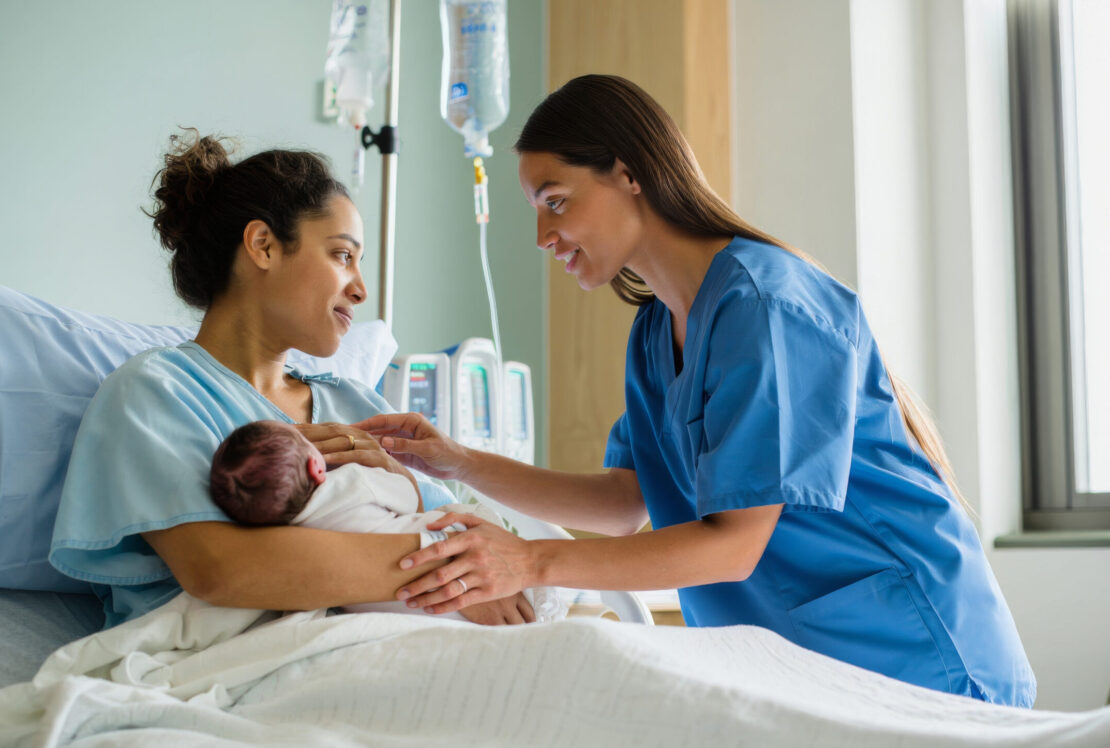 woman in hospital with new baby and midwife
