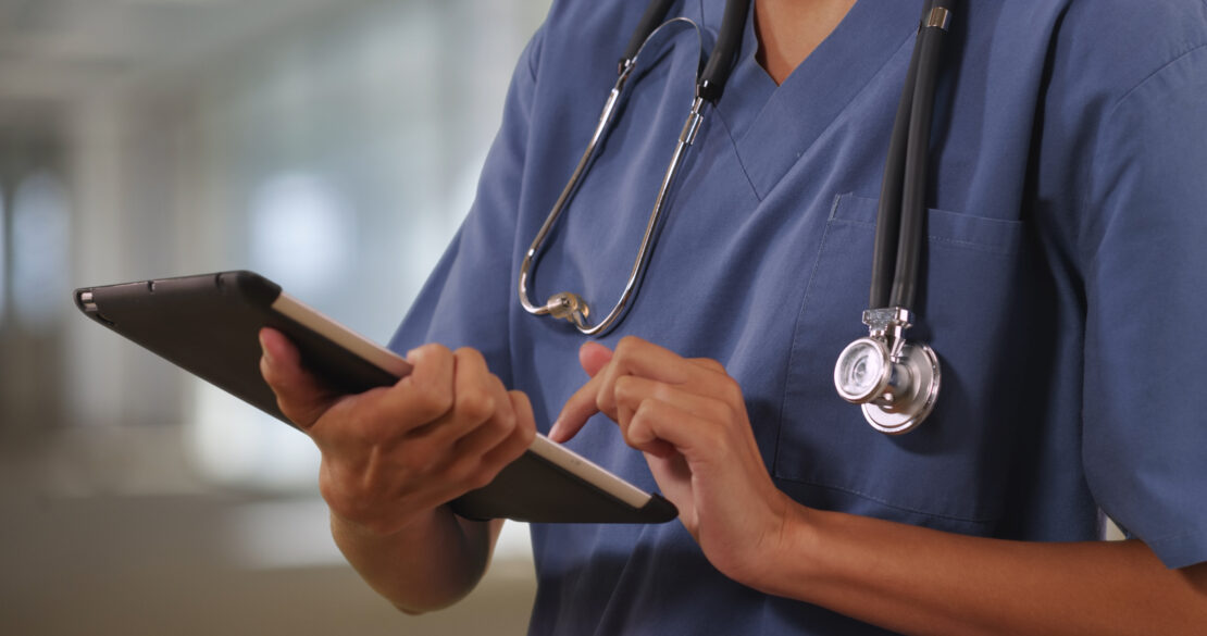 Close up of a nurse or doctor working on tablet computer whilst in a hospital