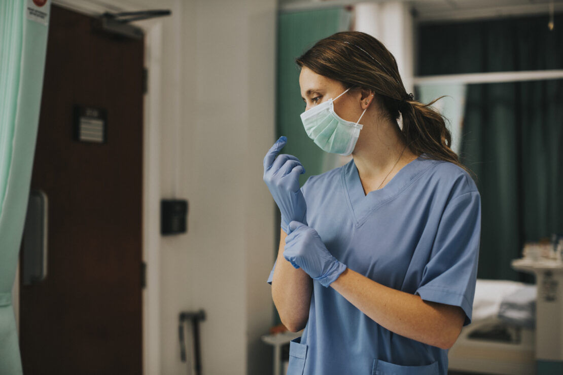 Nurse with a mask putting on gloves