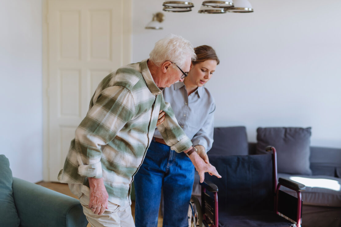 Healthcare worker holding hands and helping man at home