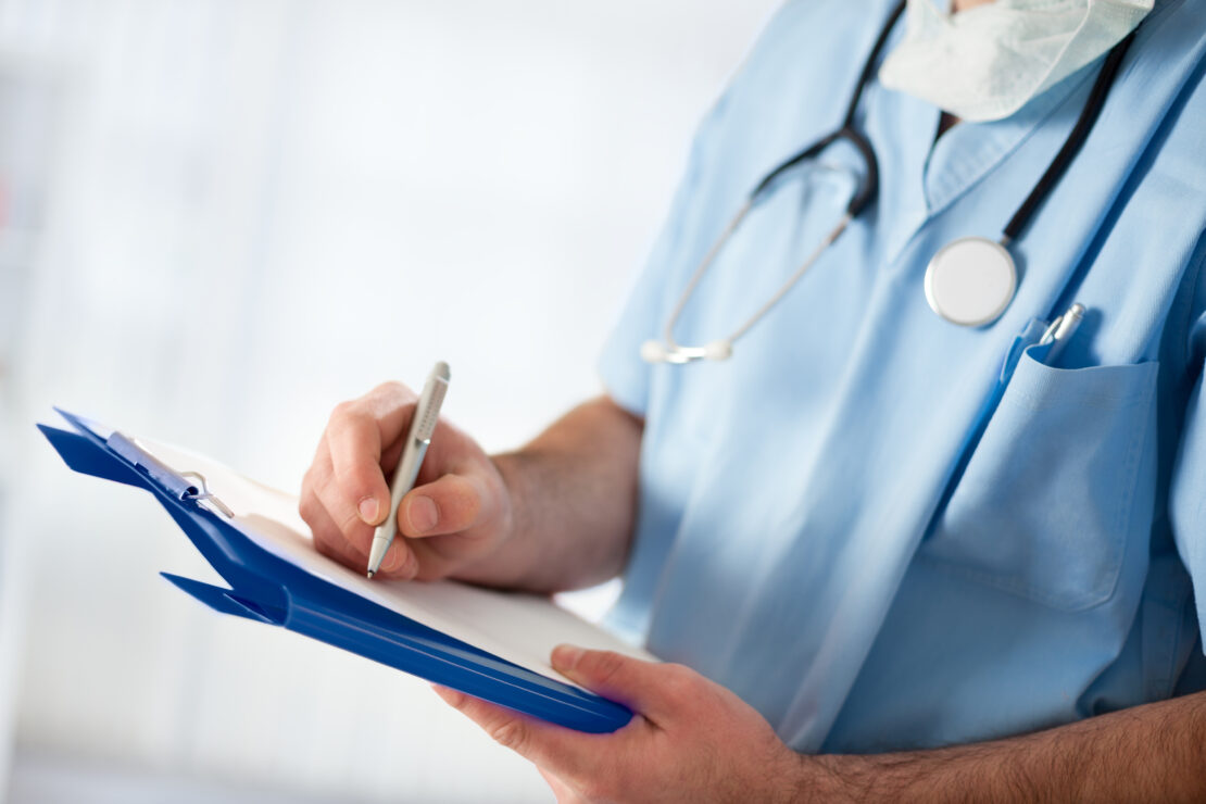 medical doctor with stethoscope writing, filing medical form
