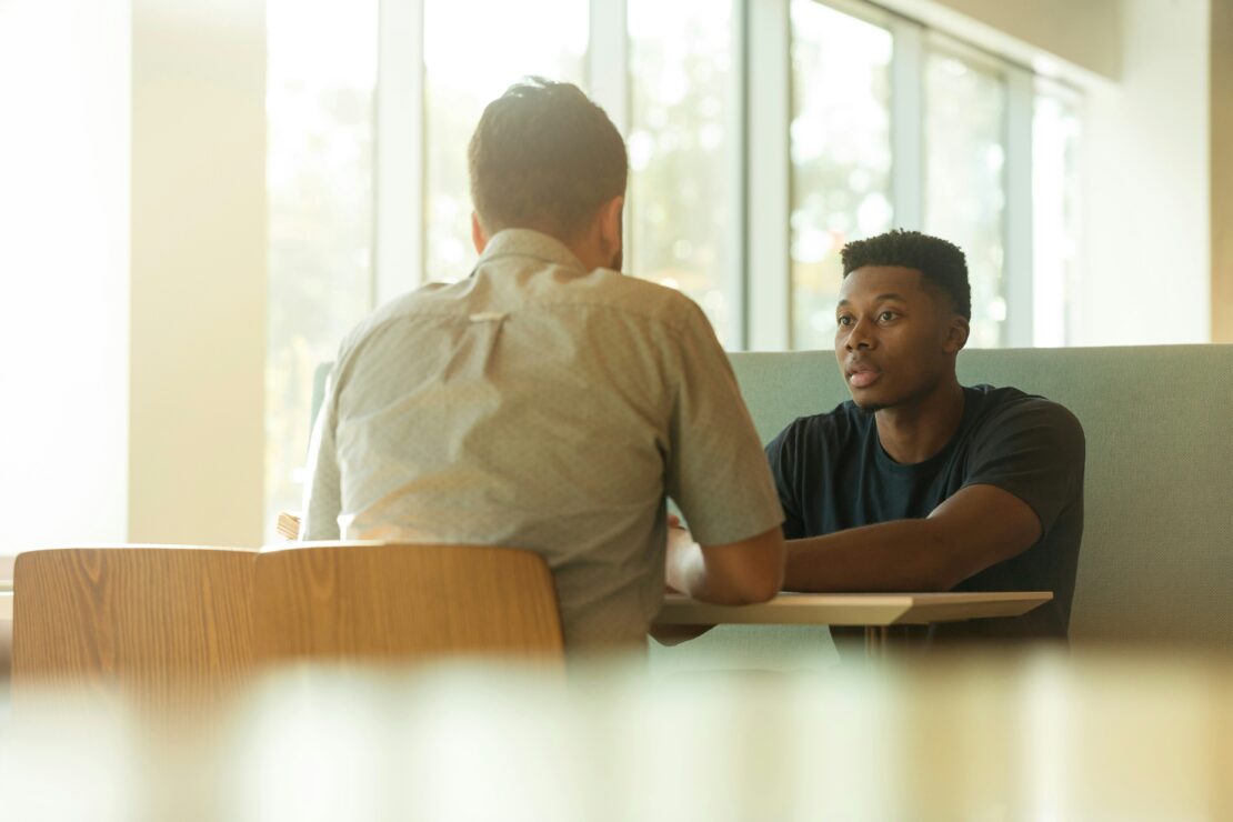 Two men talking at a cafe table