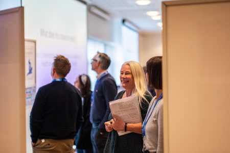 People laugh and talk during a workshop whilst looking at posters
