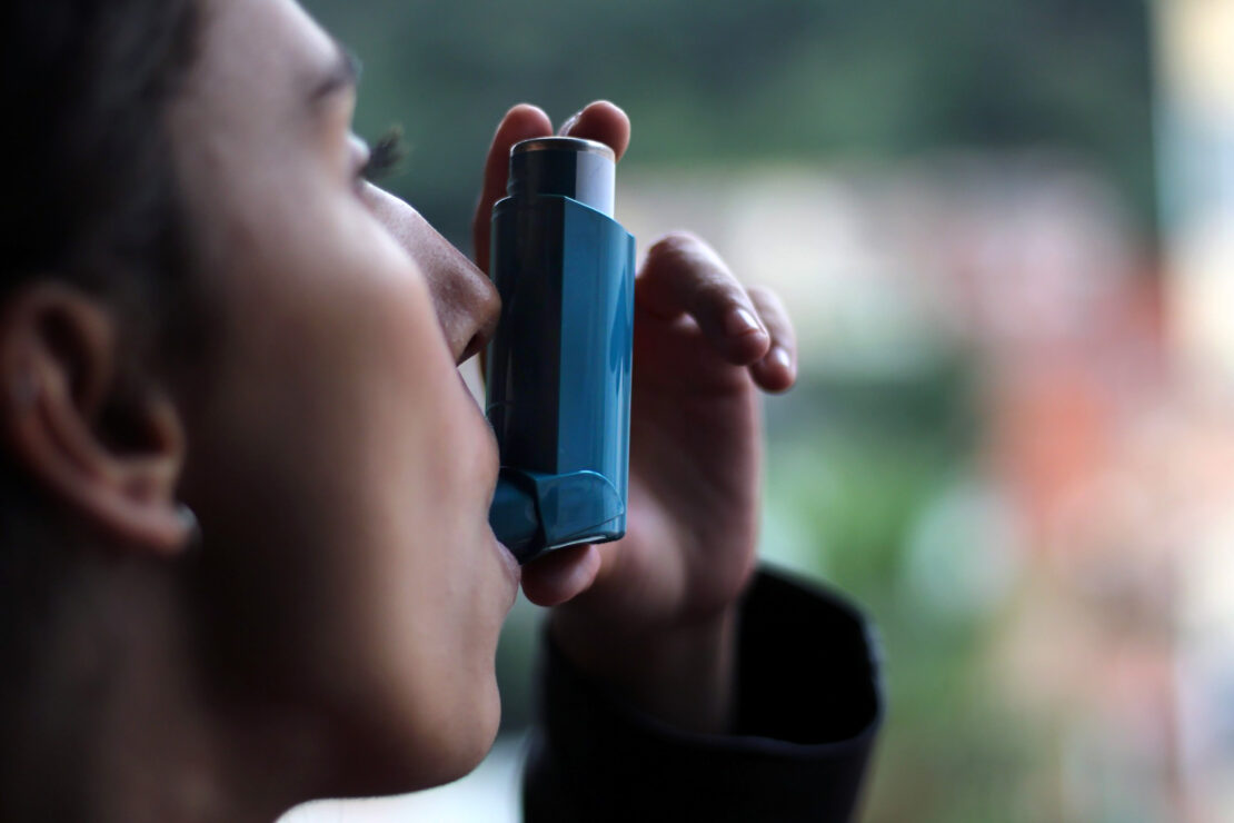 A girl using blue asthma inhaler